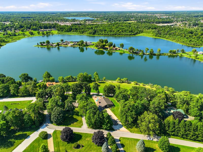 Drone photo of a wide blue lake ringed with trees and lakeside homes