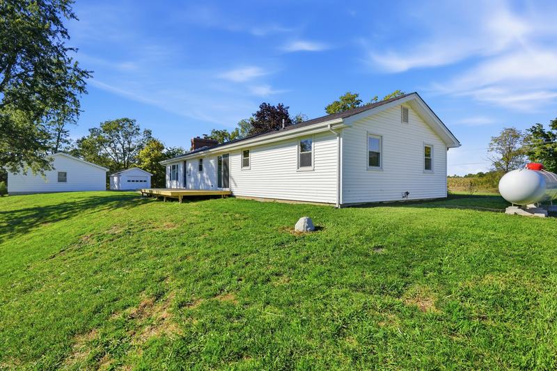 White ranch home on a sweeping green lawn under blue sky