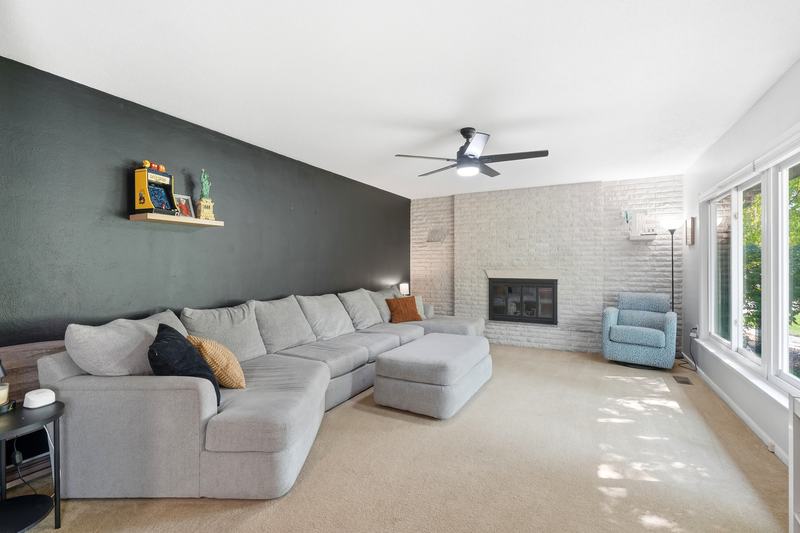 Living room with a gray sectional, tiled fireplace and natural light